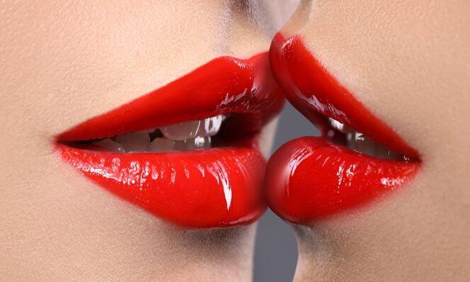 An image of two feminine lips with red lipstick almost kissing.