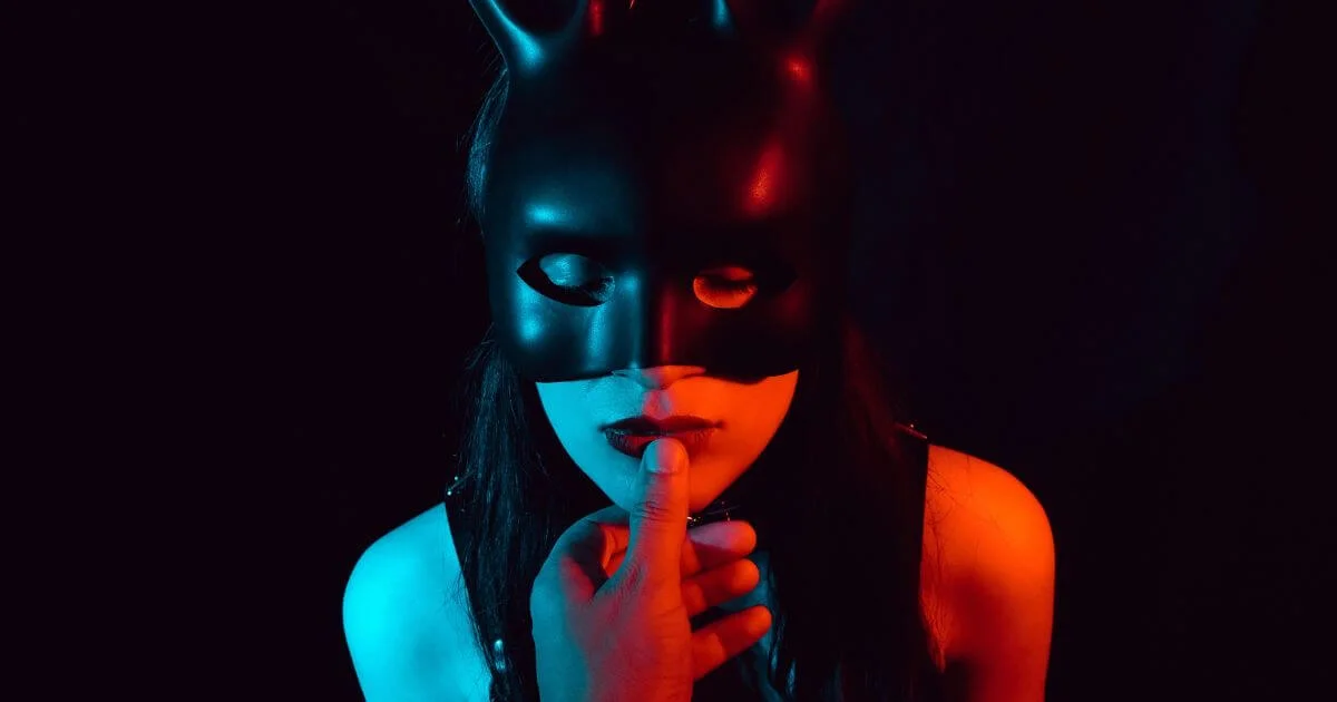 Person wearing a black mask in a BDSM setting, representing quotes about submission, surrender, trust, and power exchange.