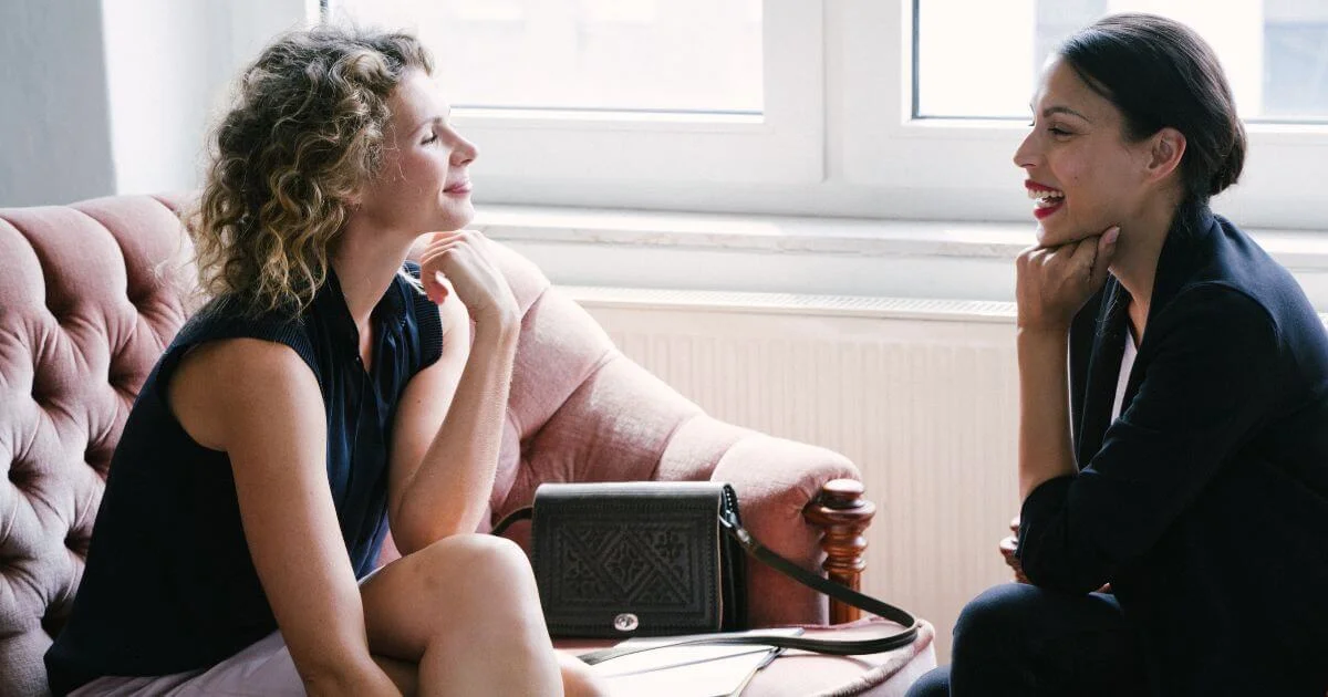 Two women talking during a private sexuality coaching session, representing supportive conversations about intimacy, communication, relationships, and sexual well-being.
