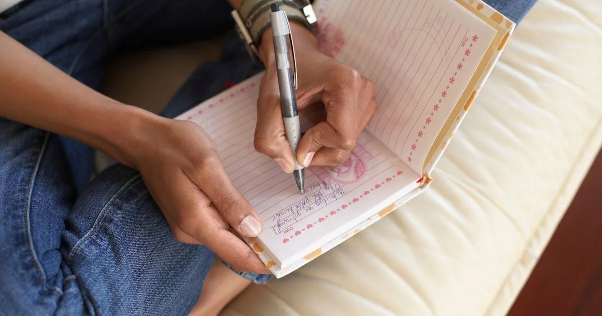 Person writing in a notebook, representing a yes no maybe list for exploring sexual interests, boundaries, consent, and BDSM negotiation.